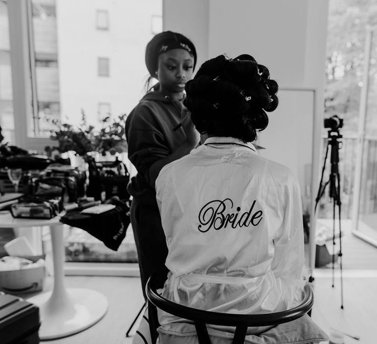 Bride wearing embroidered white satin robe as the bride gets ready for her wedding day 