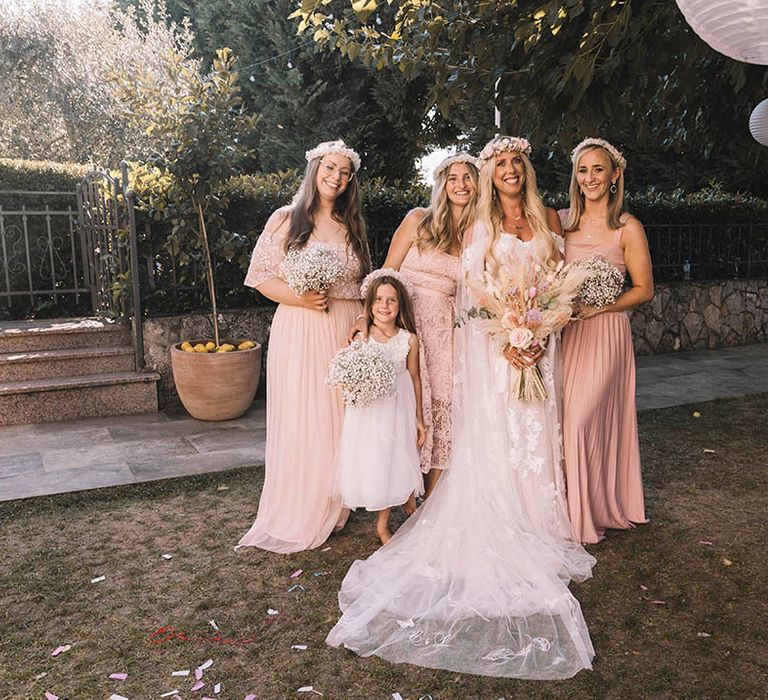 Bridal party wearing pink bridesmaid dresses with boho flower crowns and gypsophila bouquets 