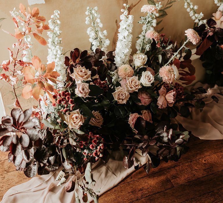 Autumnal wedding flower arrangement with pastel roses and autumnal leaves 