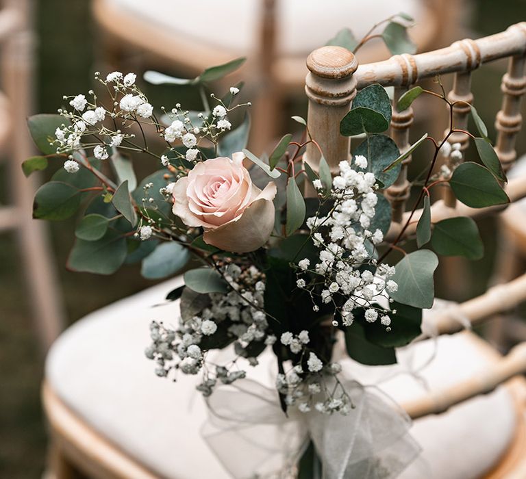 Pink rose and gypsophila wedding flower arrangement attached to the chairs at the ceremony 