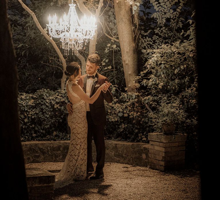 Intimate first dance for the bride and groom under chandelier 