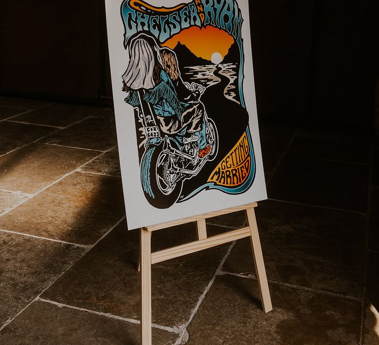 Colourful retro style wedding welcome sign with illustration of the bride and groom riding on a motorbike into the sunset 