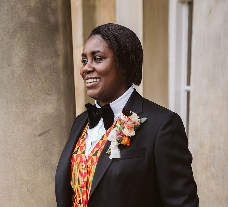 Bride wearing a black bow tie and suit jacket with traditional Ghanian patterned waistcoat 