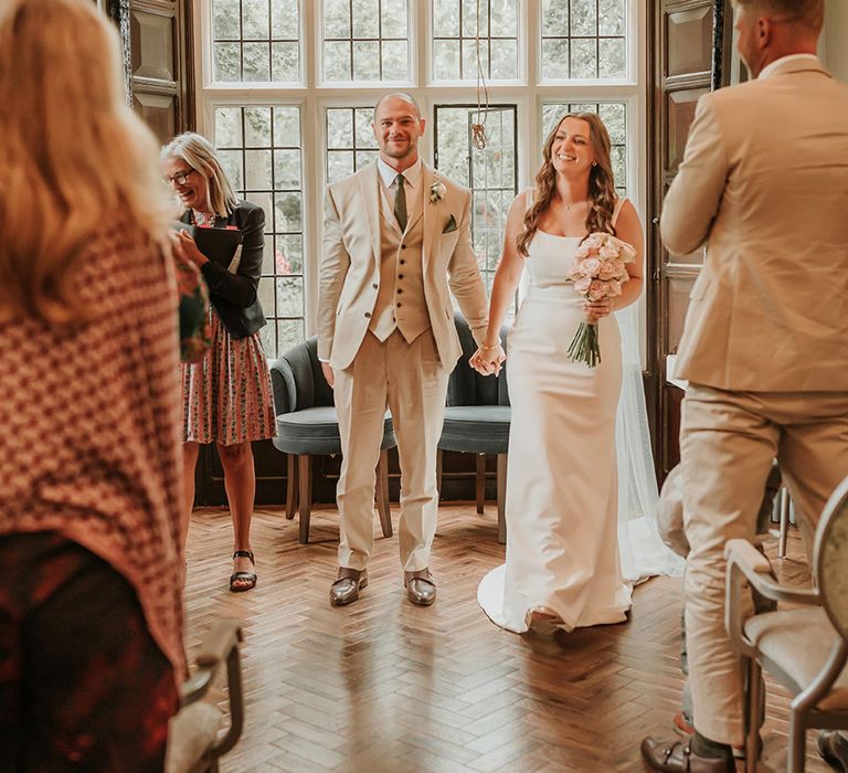 Bride in satin slip wedding dress with the groom in a three piece suit at their registry office wedding 