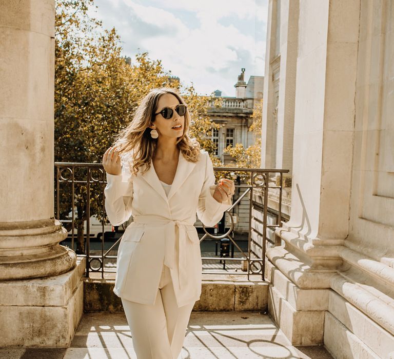 Bride in high street trouser suit and sunglasses at city elopement 