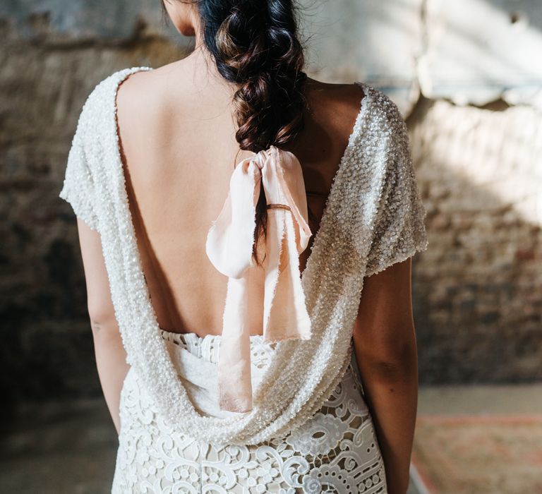 Bride in white sequin dress with low V back and bridal braid tied with ribbon 