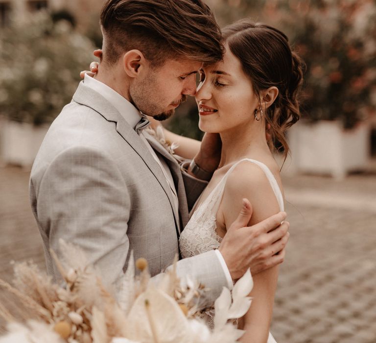 Bride and Groom embrace in garden with dried flower wedding bouquet