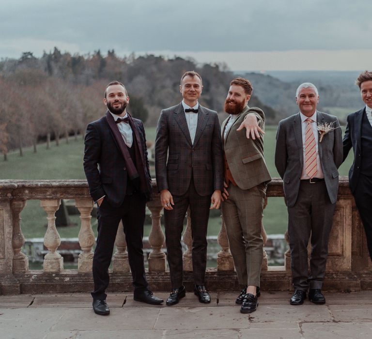 Groom poses with wedding party on the balcony of Cliveden House