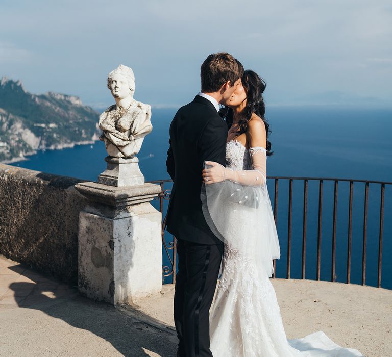 Bride and groom kissing with the Amalfi coast in the background at their Ravello wedding