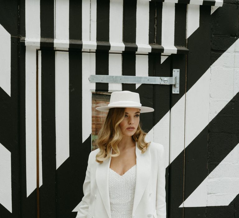 Bride with blonde wavy hair in a hat, sequin jumpsuit and blazer 