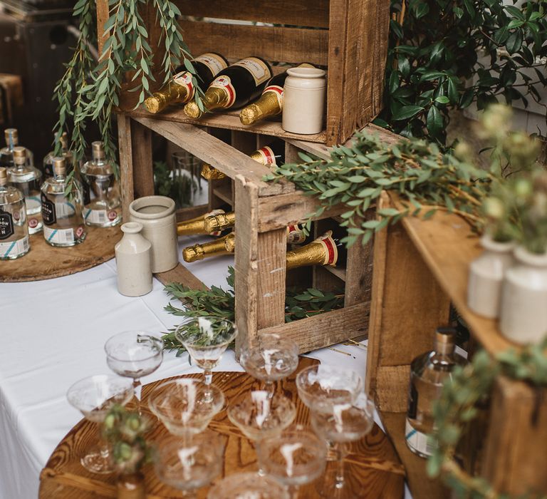 Rustic crates display champagne bottles. Champagne saucers are lined up in front of the crates and bottle of spirits are to the side. Photography by Darek Sietana.