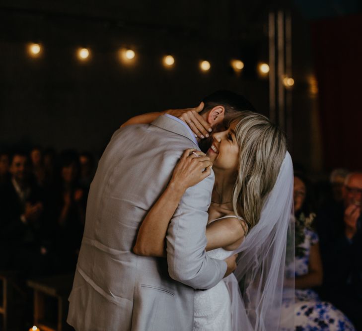 White bride and groom hugging during ceremony in front of guests