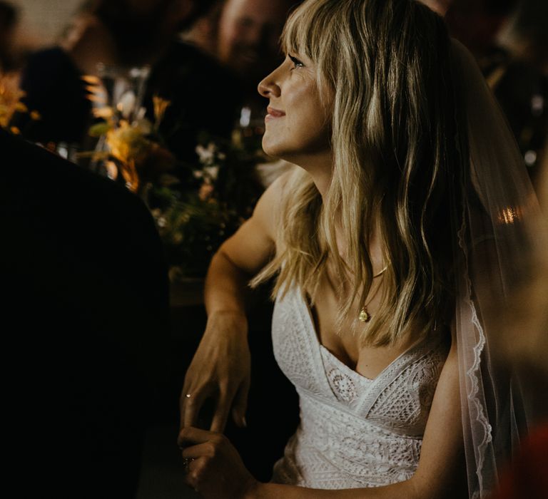 White bride with blonde hair watching speeches from table