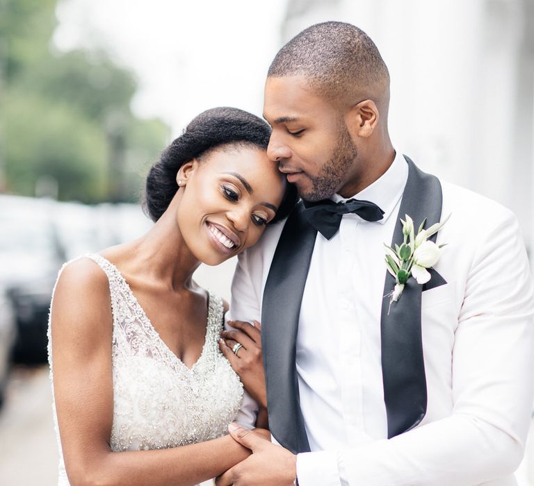 Groom kisses bride on the forehead as they walk through London