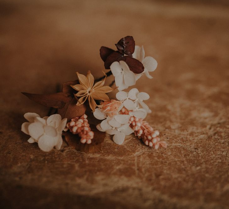 Delicate buttonhole with white and brown flowers and leaves