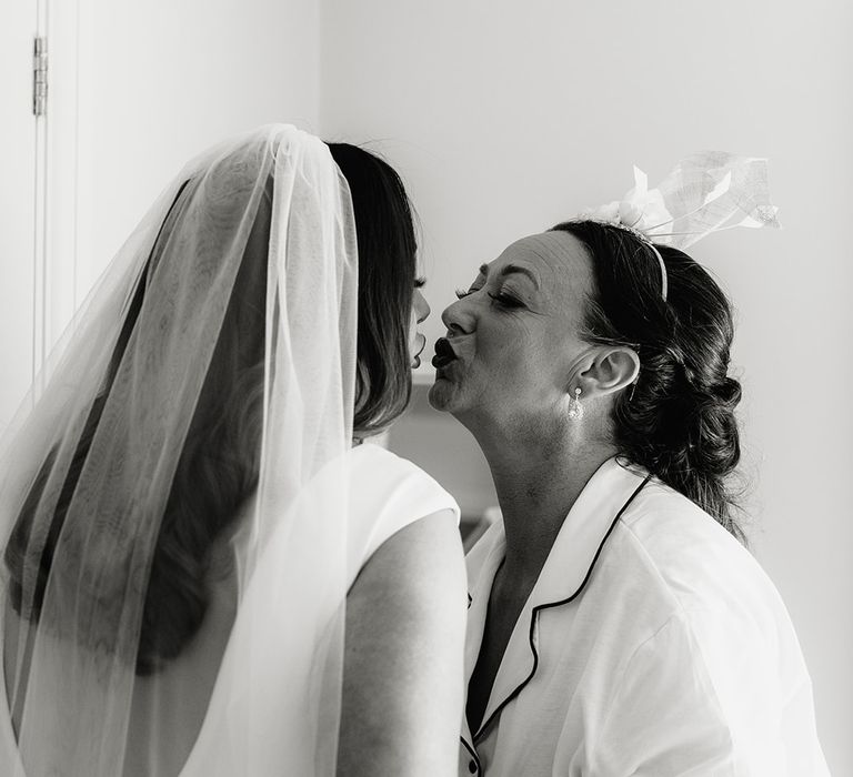 Bride in white Made With Love wedding dress and veil embracing mother of the bride in satin shirt and shorts pyjama set