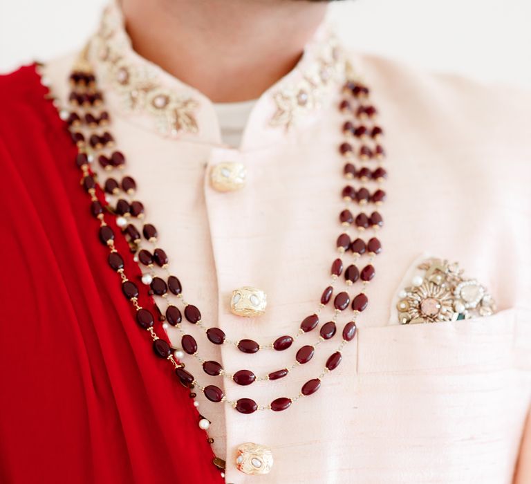 Groom wears red and pale pink suit with stone embellishment 