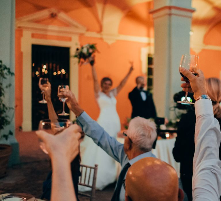 The guests raising a glass of red wine with the bride and groom