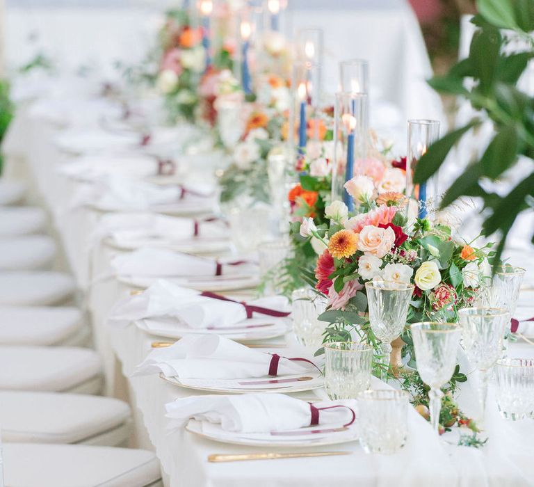 White banquet table for an outdoor Italian wedding with tapered candles and floral centrepieces