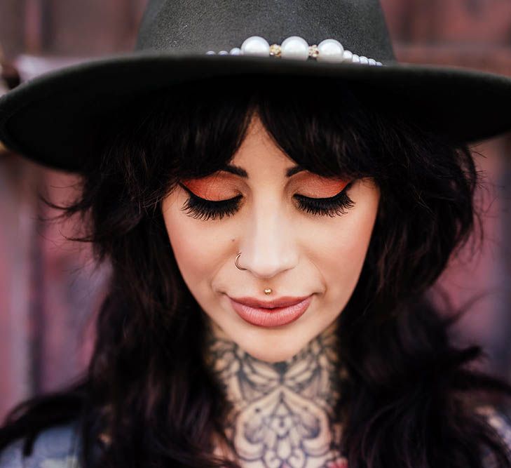 Alternative bride with neck tattoos, fedora hat and winged eyeliner 