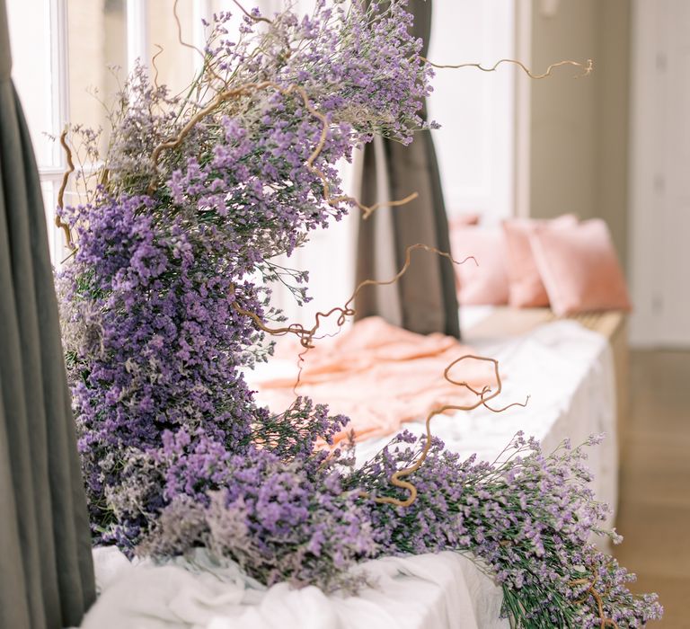 Lavender comes out of window whilst twisted branches weave in and out of floral installation 