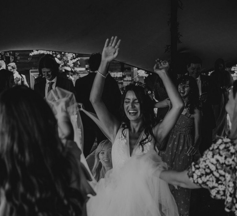 Bride dances during her wedding reception as she lifts her arms into the air for black & white photo