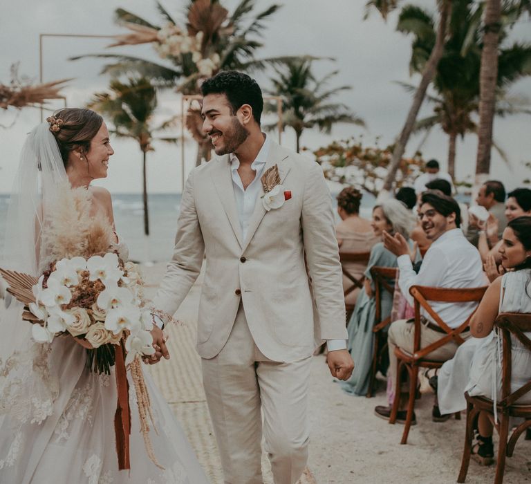 Bride & groom smile together during Mexico wedding as the beach fades into the background 