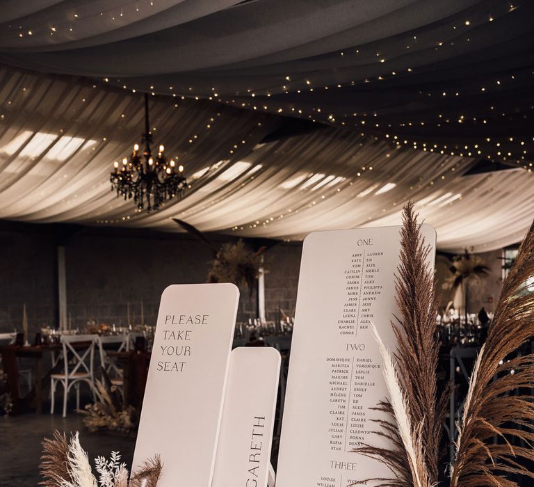 White wedding welcome signs for boho wedding reception in Dorset with pampas grass, drapery and fairy lights