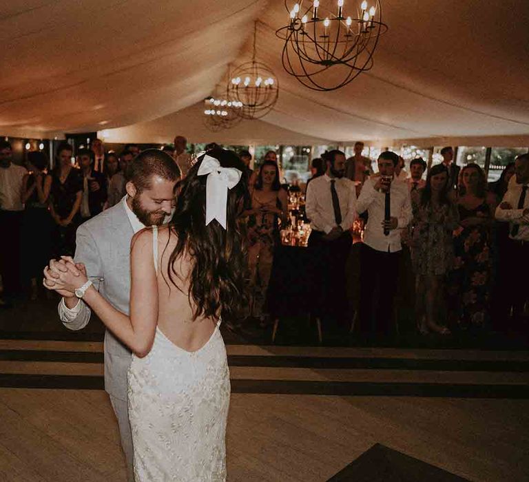 Bride in low back wedding dress with satin hair bow dances with her new husband