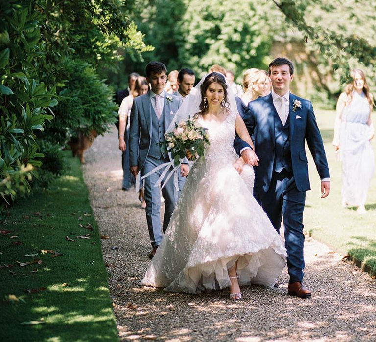 Bride & groom walk arm in arm together outdoors through Mapperton grounds