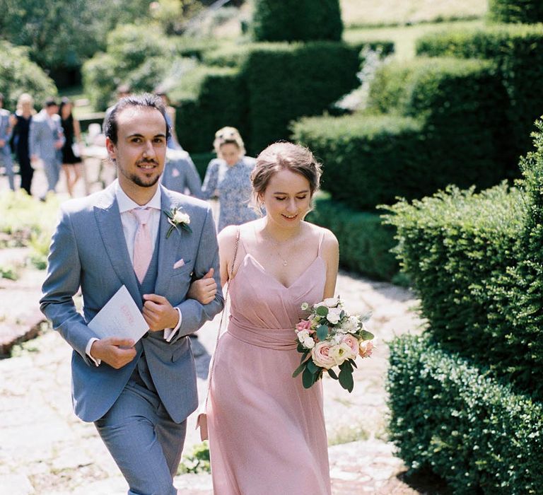 Grooms wearing powder blue suits walk down the aisle with bridesmaids wearing pale pink dresses 