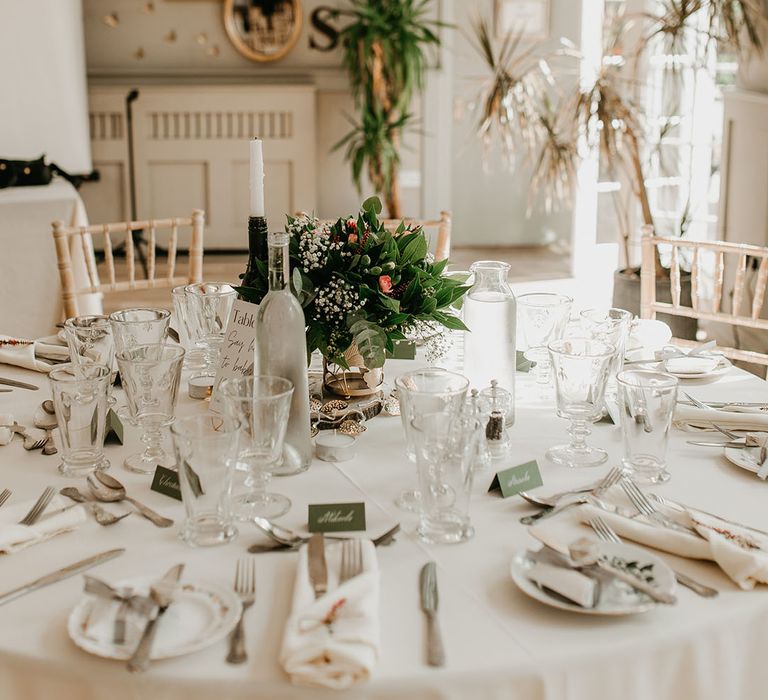 Floral bouquets sit in the middle of the table with white tablecloths and sage green accent colour