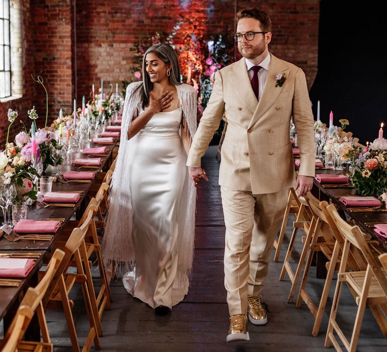 Bride and groom walking through their colourful wedding reception at The Loft Studios London 