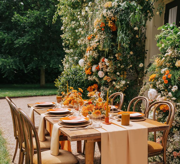 Orange pillar and taper candles, natural wicker place mats and orange tableware 