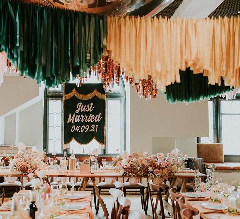 Green tassel Just Married banner sits at the top of reception venue complete with wooden tables 