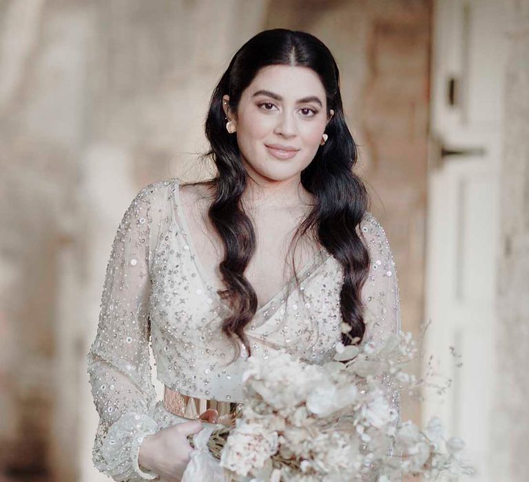 Bride with long wavy hair in a sparkly wedding dress holding a dried flower wedding bouquet 