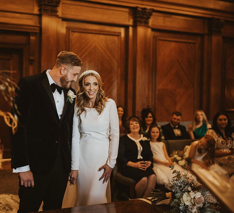 Intimate registry office wedding with groom in a tuxedo and bride in a long sleeve wedding dress 