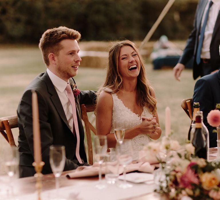 Bride and groom laugh at wedding speeches