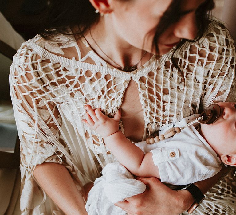 Bride holds her baby on the morning of her wedding day