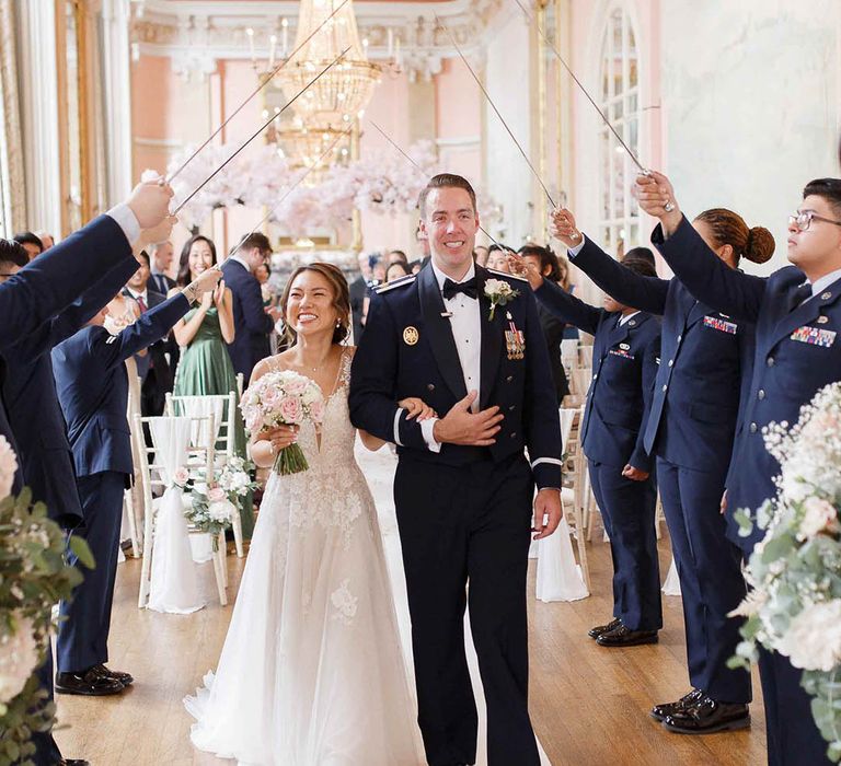 Bride & groom leave under Sabre Arch after wedding ceremony 