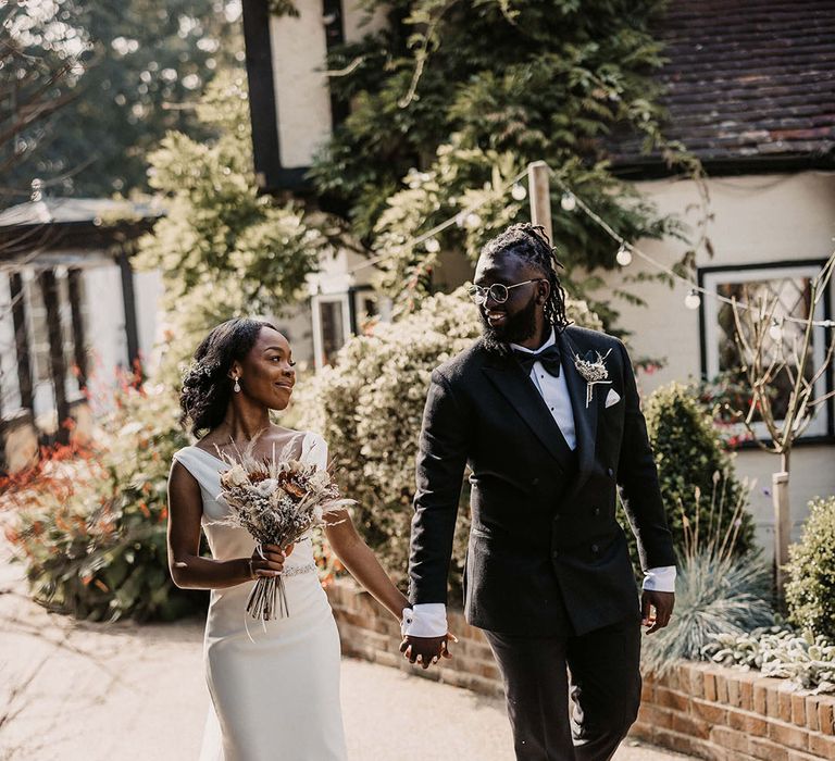 Bride & groom hold hands and walk together on their wedding day