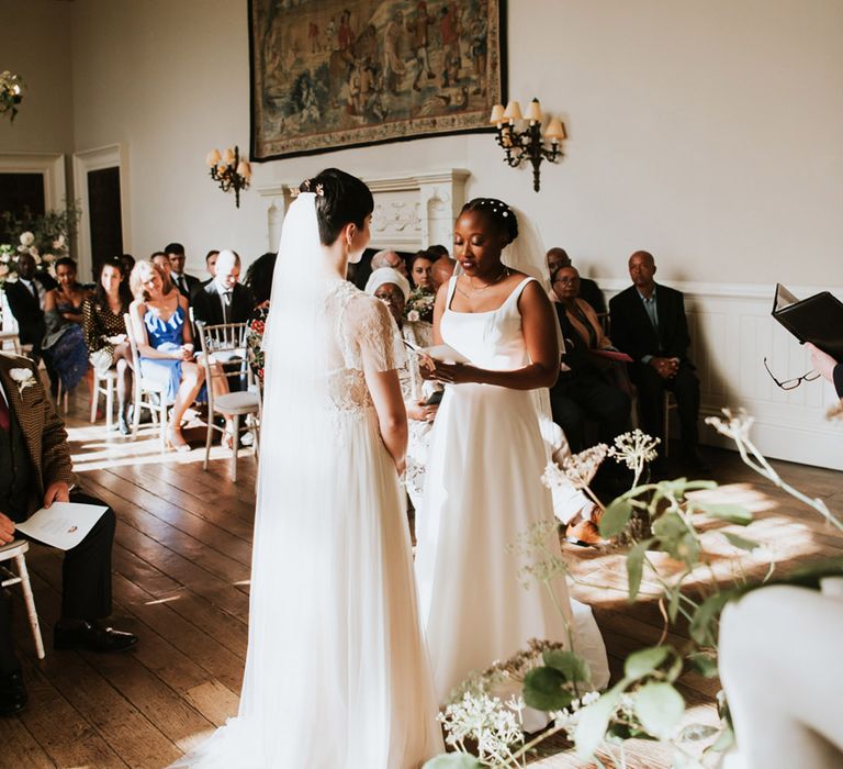 Black bride with short hair decorated with peal clips in an Essense of Australia wedding dress reading her personalised wedding vows 