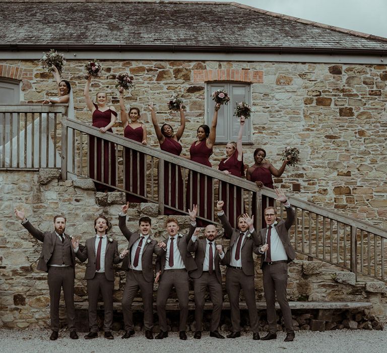 Bridesmaids & grooms hold their arms in the air on wedding day at Nancarrow Farm