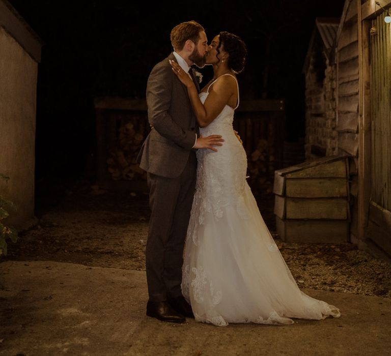 Bride & groom stand beneath festoon lighting on their wedding day