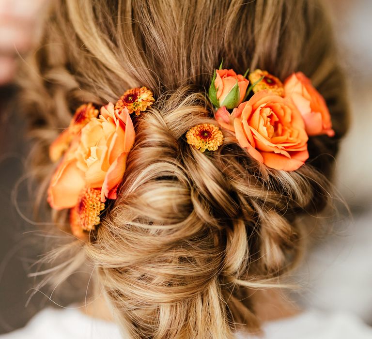 Bride with curled updo hair decorated with orange roses