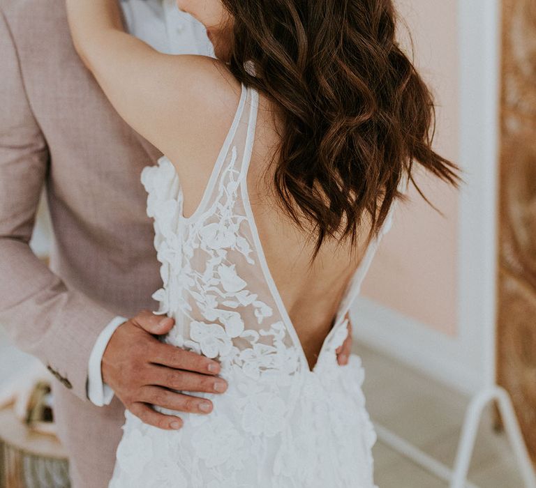 Bride with low back wedding dress wears her dark hair down with loose curls and a fishtail plait 