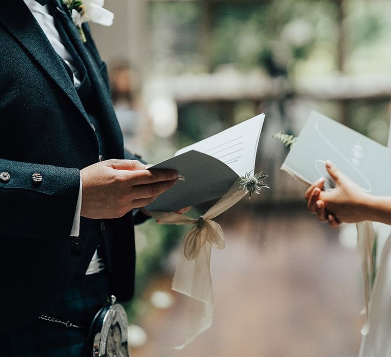 Bride and groom reading their personalised wedding vows at the altar 