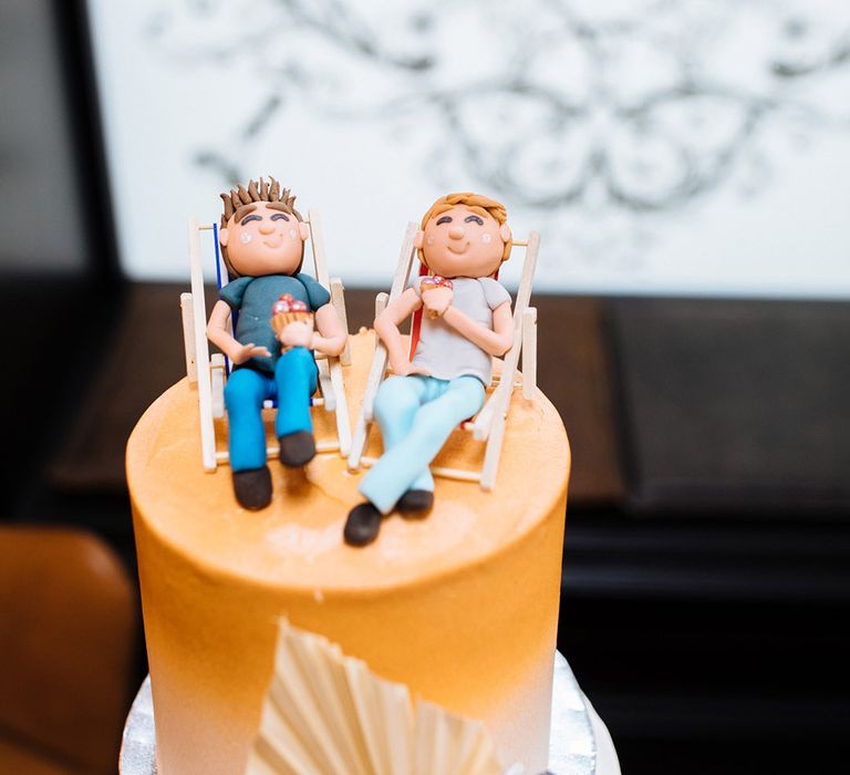 Orange to white ombré frosted wedding cake with personalised cake toppers of the grooms on deck chairs