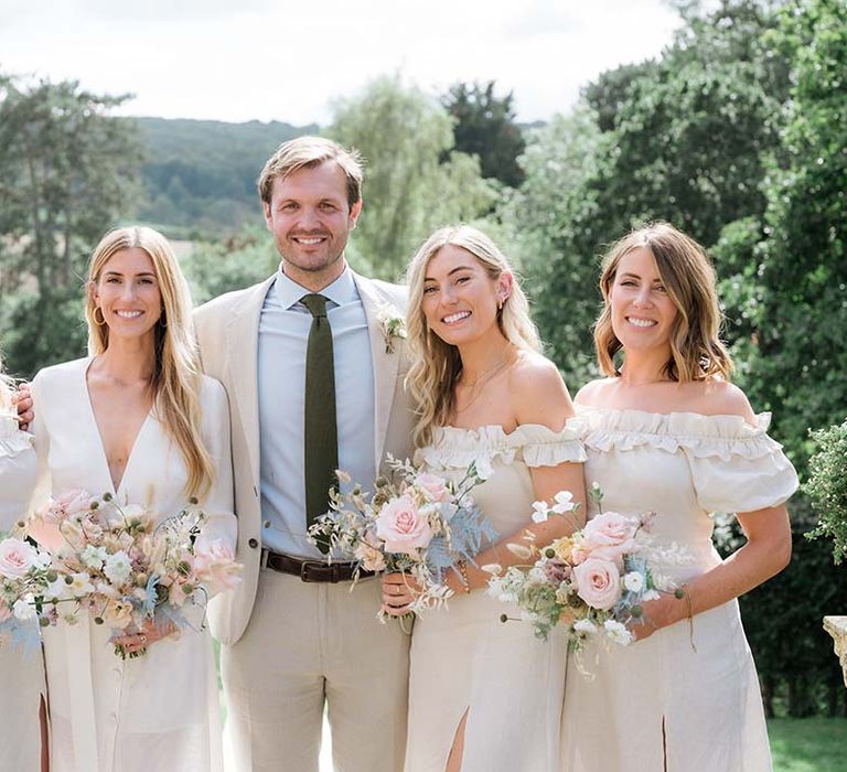 Groom with the bride wearing Bon Bride and bridesmaids in off the shoulder dresses and pastel pink and blue bouquets