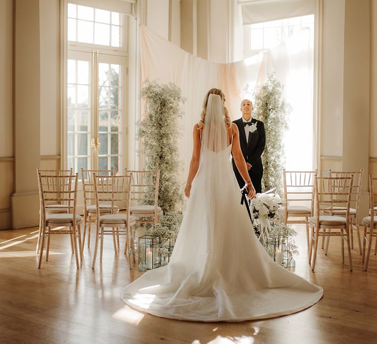 Bride in a princess wedding dress with puddle train and cathedral length wedding veil standing at the aisle at Hodsock Priory 